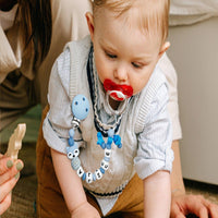 Un bébé porte une attache tétine personnalisé de couleur bleu Charlie le renard - Mon Doux Cocon