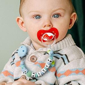 Un bébé a une tétine avec une attache tétine personnalisable Charlie le renard - Mon Doux Cocon